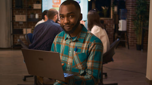 Rear view of man using laptop while standing in city