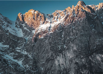 Snow covered rocky mountains against clear sky