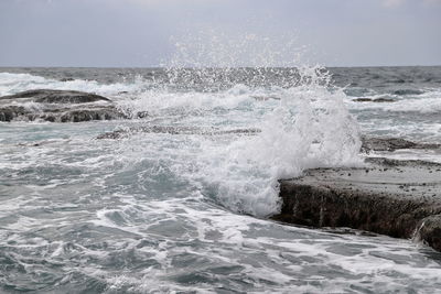 Waves splashing in sea against sky