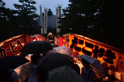 People at illuminated city against sky at night