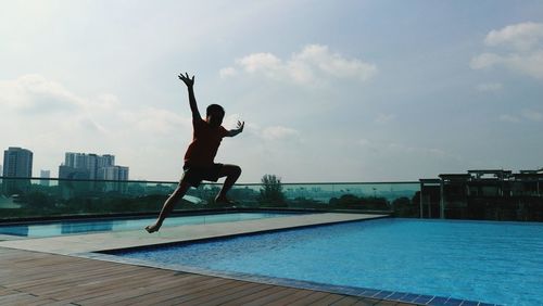 Man jumping in swimming pool against sky