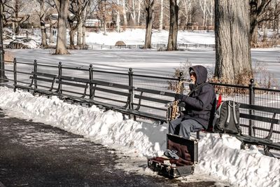 Man sitting on snow covered railing