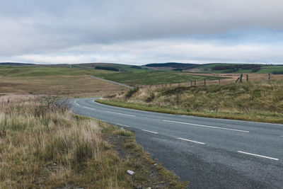 Road amidst field against sky