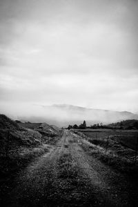 Dirt road along landscape against sky