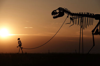 Silhouette man standing on field against sky during sunset