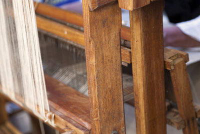 Man weaving a canvas from flax fibers with an antique hand weave machine.