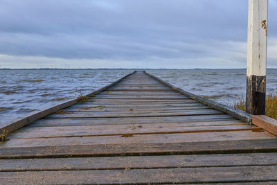 Wooden pier over sea against sky