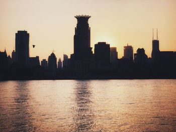 Silhouette buildings in city against sky during sunset