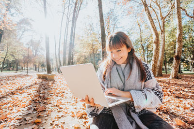 Young woman using laptop while sitting on field