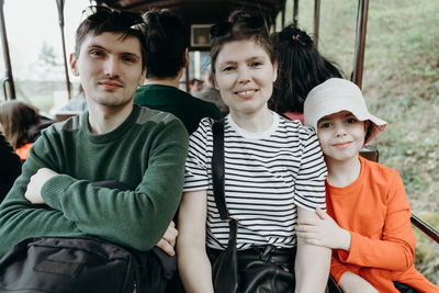 A caucasian family travels on a train in a nature reserve.