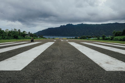 Surface level of country road against cloudy sky