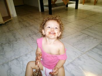 Smiling girl eating chocolate with messy mouth at home