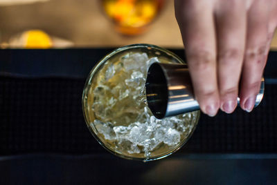 Cropped hand of woman pouring alcohol in glass on table at restaurant