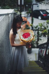 High angle view of young woman holding bouquet while standing on stairs