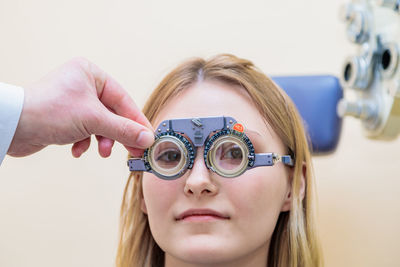 A male optometrist checks the eyesight of a young girl with a trial frame