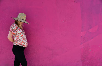 Full length of woman standing against pink wall