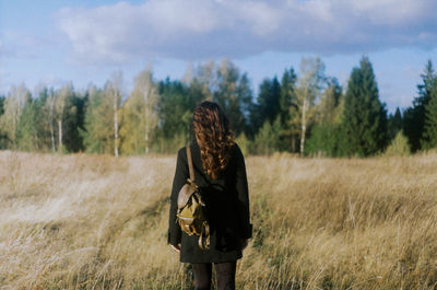 Rear view of man standing on field against sky