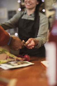 Cropped image of customer giving credit card to owner at checkout counter in store