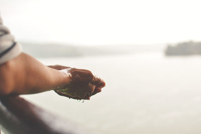 Close-up of hand with sea in background