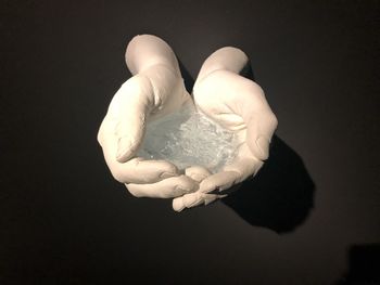 Close-up of hand holding ice cream against black background