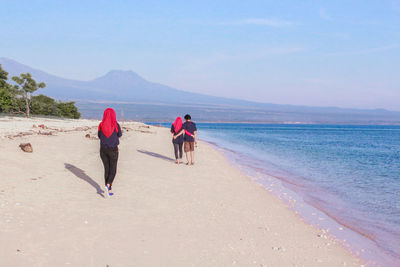 Rear view of people walking on beach