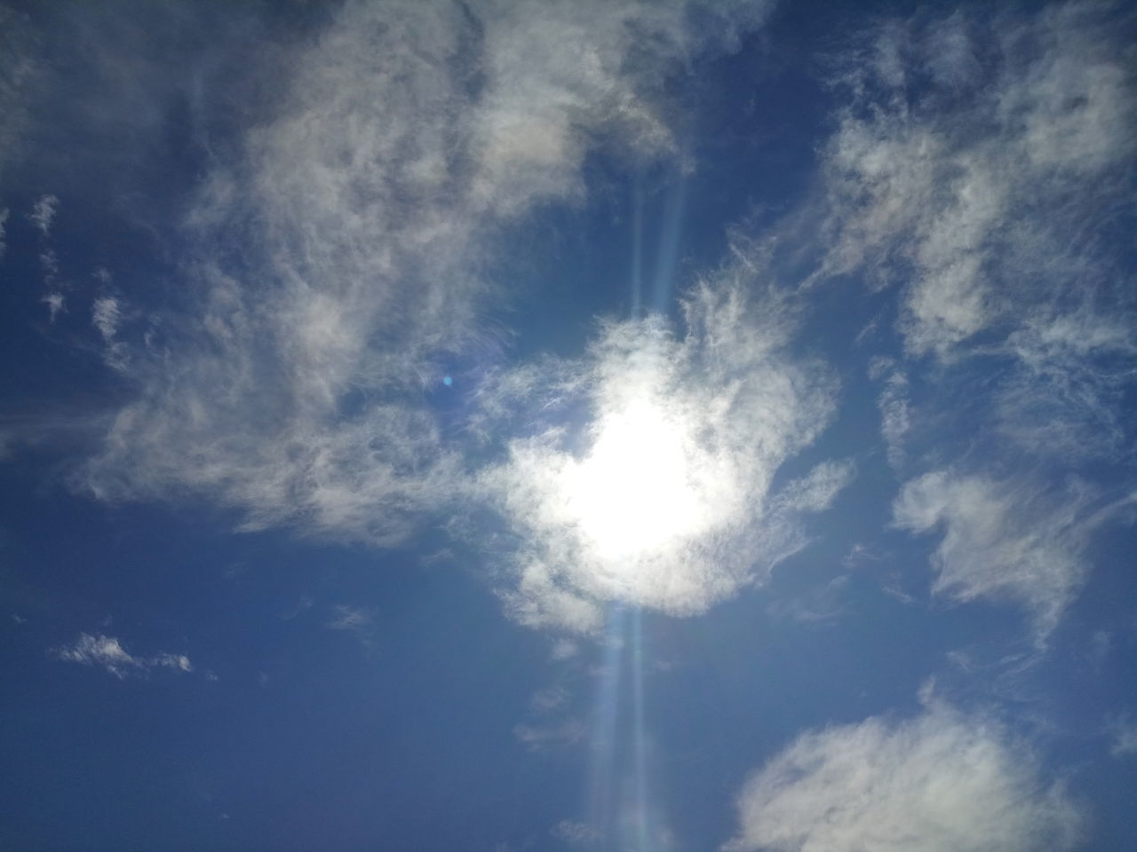 LOW ANGLE VIEW OF SUN STREAMING THROUGH CLOUDS