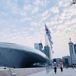 People by buildings against sky in city