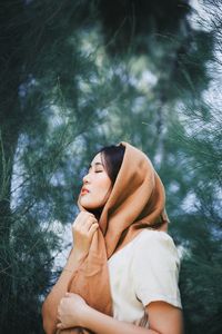 Woman with eyes closed against trees