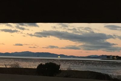 Scenic view of sea against cloudy sky at sunset