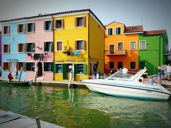 Boats moored in canal by building against sky