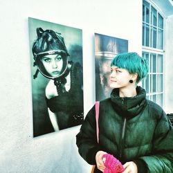 Portrait of young woman standing against wall