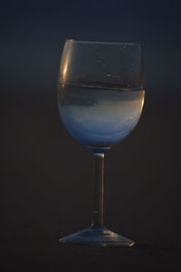 Close-up of wineglass on table against black background