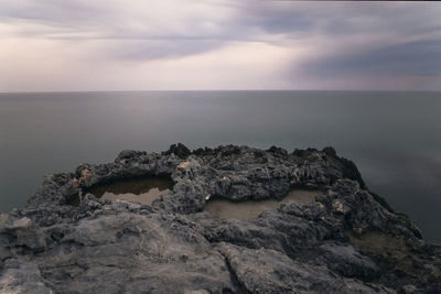 Rock formation in sea against sky