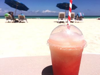 Close-up of drink on beach against sky