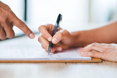 Close-up of woman hand holding pen on table