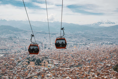 Overhead cable cars over cityscape against sky
