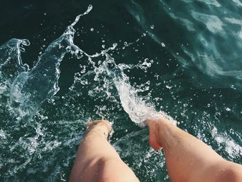 Low section of woman splashing water in sea