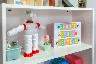 Recycled toy robot made with plastic packages and lightbox with ecology text on shelf in classroom