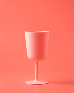 Close-up of wineglass on table against red background