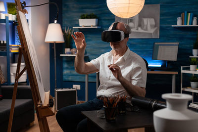 Senior man using vr headseat sitting at workshop