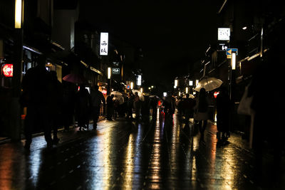 People walking on wet street at night