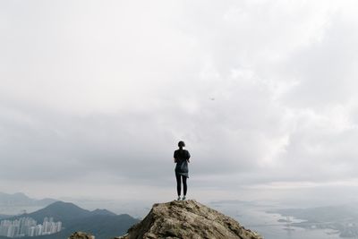 Woman standing on top of mountain against cloudy sky