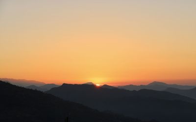 Scenic view of silhouette mountains against romantic sky at sunset