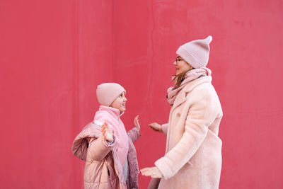 Mother and daughter in pink clothes on a red background are having fun