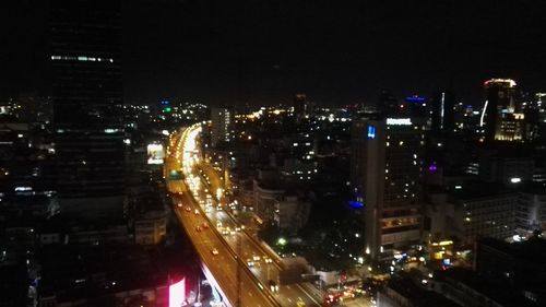 High angle view of illuminated street amidst buildings in city at night