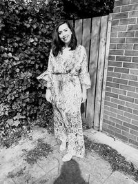 Portrait of a smiling young woman standing against brick wall