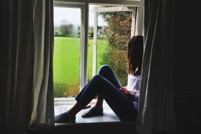 Woman sitting on window sill