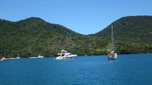 Boats on sea against mountains