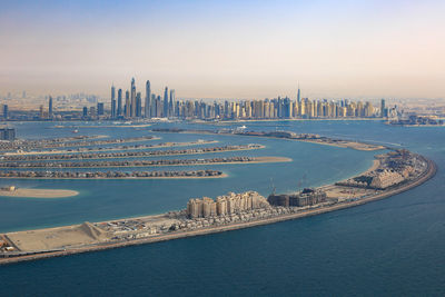 High angle view of city by sea against sky