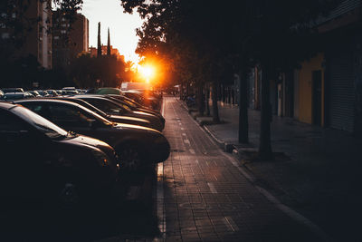 Cars on street amidst buildings in city during sunset